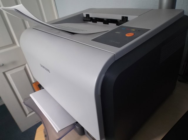 Tlačiareň na laserovú tlač s papierom pripraveným na tlač.